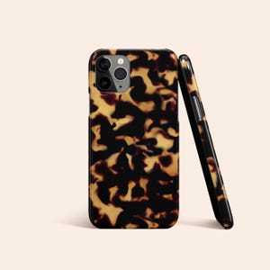 Op de afbeelding: Een telefoonhoesje met een zwart en bruin schildpadpatroon voor een iPhone.