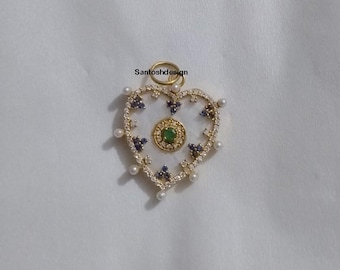 May include: A gold heart-shaped pendant with a white centre and a green gemstone surrounded by blue gemstones. The pendant is decorated with small white pearls.