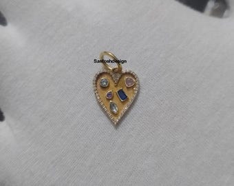 May include: A gold heart-shaped pendant with various coloured gemstones and small white diamonds around the edge. The pendant has a small loop at the top for a chain. The text "Santoshdesign" is visible on the pendant.
