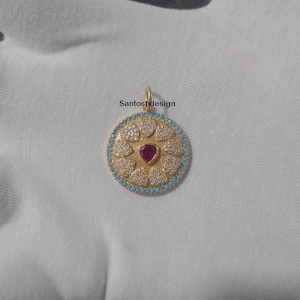 May include: Gold-toned pendant with a central heart-shaped ruby, surrounded by heart-shaped clear stones and a turquoise border. The pendant has a loop at the top for a chain. The text "Santoshdesign" is printed on the image.