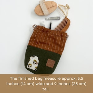 May include: A brown and green drawstring bag with a floral print. The bag measures 5.5 inches wide and 9 inches tall.