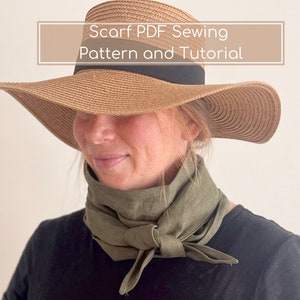 Op de afbeelding: Een vrouw draagt een strohoed met brede rand en een zwarte band en een olijfgroene sjaal om haar nek geknoopt. De afbeelding bevat de tekst "Scarf PDF Sewing Pattern and Tutorial".