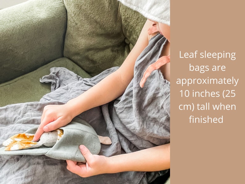 May include: A child holds a gray and brown fabric sleeping bag with bunny ears. Leaf sleeping bags are approximately 10 inches (25 cm) tall when finished.