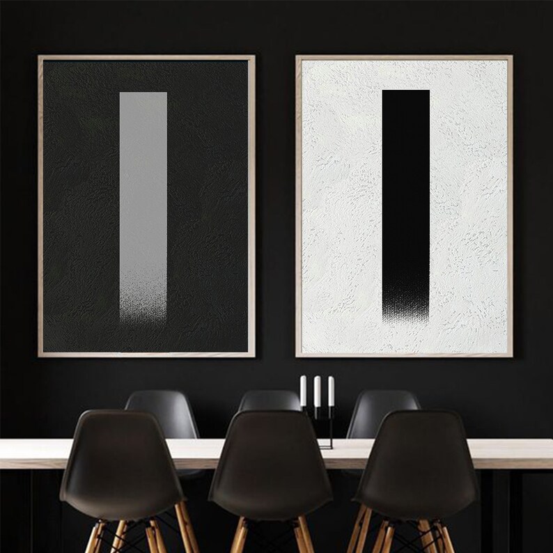 May include: Two framed abstract art prints with black and white vertical lines. The print on the left has a gray line on a black background. The print on the right has a black line on a white background.