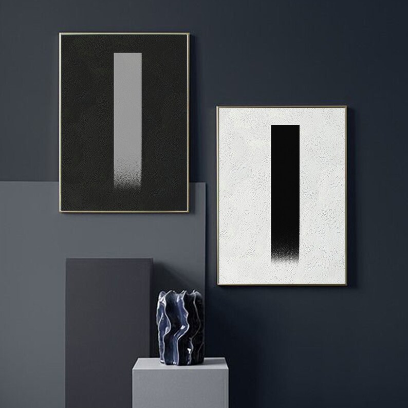 May include: Two framed abstract art prints with a black and white color scheme. The prints feature a vertical rectangle shape with a gradient effect.