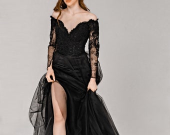 May include: A black off-the-shoulder gown with long sleeves and a flowing skirt. The bodice features intricate lace detailing, and the skirt has a high slit. The dress is made of a combination of fabrics, including lace and tulle.