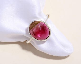 Könnte beinhalten: Ein Silberring mit einem glatten, ovalen Cabochon-Edelstein, der einen Farbverlauf von Dunkelrosa bis Braun aufweist. Der Stein ist in eine schlichte, polierte Silberfassung mit einer dünnen, glatten Ringschiene eingefasst und zeigt einen natürlichen Farbverlauf.