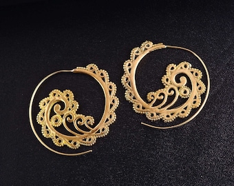 May include: A pair of gold-toned hoop earrings featuring an open spiral design. Each earring is crafted with intricate filigree metalwork, including small beaded edges and swirling patterns that extend from the center of the hoop.