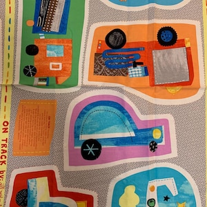 May include: A colourful fabric panel featuring a variety of vehicles, including a train, a boat, a truck, a plane, and a police car. The panel is designed for quilting or other craft projects. The text "ON TRACK by..." is visible in the bottom left corner.