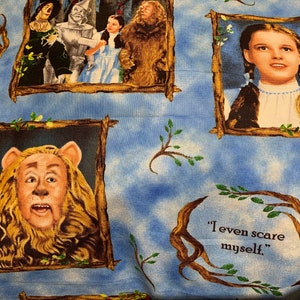 May include: A blue and white fabric with a repeating pattern of framed images from the Wizard of Oz movie. The images include Dorothy, the Cowardly Lion, the Tin Man, the Scarecrow, and the Wicked Witch of the West. The fabric also includes the text "We're off to see the Wizard of Oz" and "I even scare myself."