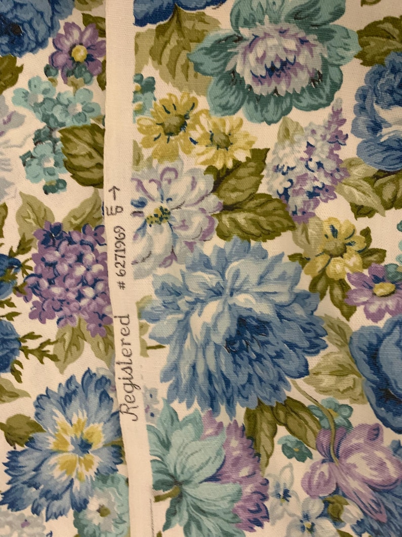 May include: Floral fabric with a pattern of large blue, purple, and yellow flowers on a white background. The fabric has a Registered label with the number 6271969.