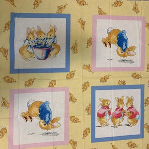 Peut inclure: Un tissu jaune avec un motif répété de lapins. Le tissu présente quatre carrés avec différentes illustrations de lapins. Un carré montre trois lapins tenant un bol, un autre montre un lapin tenant un bol, et les deux autres carrés montrent des lapins portant des vestes bleues.