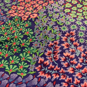 May include: A close-up of a fabric with a floral pattern. The design features various floral arrangements in shades of pink, green, and purple against a dark blue background. The flowers are arranged in a patchwork style, creating a visually appealing textile.