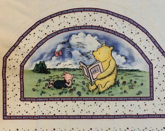 May include: A Winnie the Pooh and Piglet fabric panel with a white background and a blue sky. The panel features Winnie the Pooh reading a book that says "ABC" to Piglet. The panel is surrounded by a red and blue border with white polka dots.