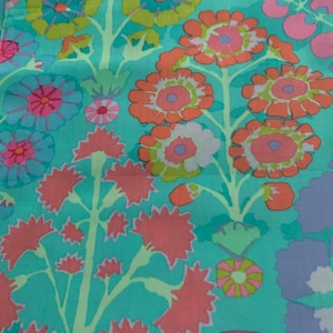 May include: A colourful floral fabric with a repeating pattern of stylized flowers in shades of orange, pink, blue, and purple against a teal background. The design includes various flower shapes and sizes, with green stems and leaves.