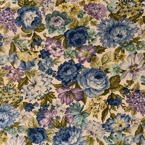 May include: Floral fabric featuring a dense pattern of blue, purple, and yellow flowers with green leaves on a cream background. The flowers include roses, hydrangeas, and other blooms, creating a vintage aesthetic.