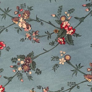 May include: A blue fabric with a floral pattern. The flowers are pink, red, and white with green leaves.