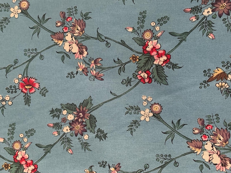 May include: A blue fabric with a floral pattern. The flowers are pink, red, and white with green leaves.