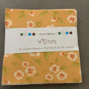 May include: A stack of square fabric pieces with pinked edges, featuring a yellow background with a repeating pattern of white flowers and green leaves. A white paper band wraps around the centre with the text moda Whimsy by Joanna Figueroa, Fig Tree & Co. for moda.