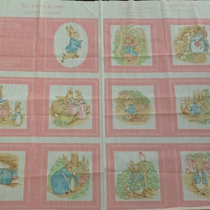 Peut inclure: Un panneau de tissu avec des illustrations de "The Tale of Peter Rabbit". Le motif comprend des bordures roses et diverses scènes de lapins dans un cadre de jardin. Le texte "THE TALE OF PETER RABBIT PICTURE BOOK" est visible.