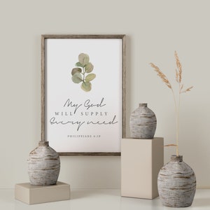 May include: A framed print with a watercolor illustration of a eucalyptus branch and the text "My God will supply every need Philippians 4:19". The print is displayed on a white wall with two decorative vases and a dried grass arrangement.