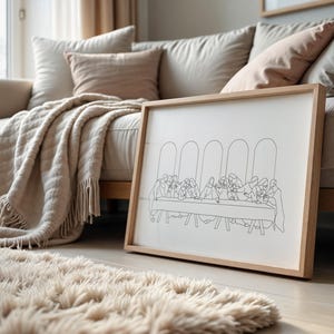 Pu&ograve; includere: Un disegno in bianco e nero a linea della Ultima Cena incorniciato. Il disegno &egrave; su sfondo bianco ed &egrave; incorniciato in una cornice in legno naturale. La cornice &egrave; appoggiata su un divano marrone chiaro con una coperta bianca.