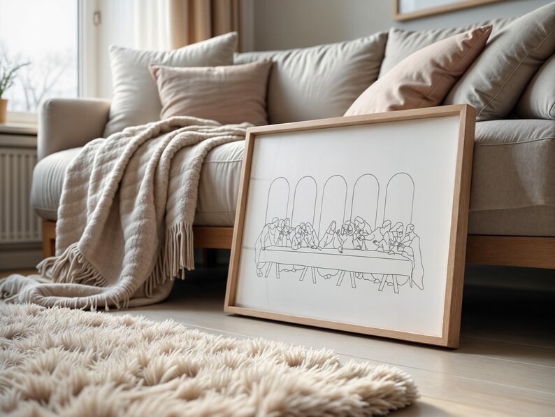 Pu&ograve; includere: Un disegno in bianco e nero a linea della Ultima Cena incorniciato. Il disegno &egrave; su sfondo bianco ed &egrave; incorniciato in una cornice in legno naturale. La cornice &egrave; appoggiata su un divano marrone chiaro con una coperta bianca.