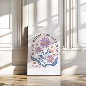 Könnte beinhalten: Ein weißes Poster mit schwarzem Rahmen, das ein Blumenmuster mit rosa, lila und orangefarbenen Blumen zeigt. Der Text auf dem Poster lautet "Bloom where God plants you."