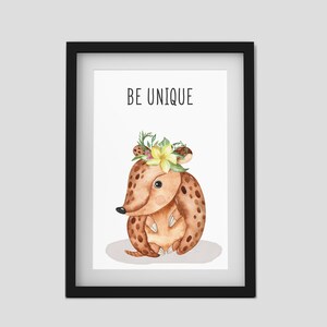 Puede incluir: Una impresi&oacute;n enmarcada con una ilustraci&oacute;n de acuarela de un armadillo marr&oacute;n con una corona de flores. El texto "BE UNIQUE" est&aacute; impreso sobre el armadillo.