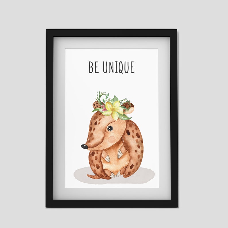 Puede incluir: Una impresi&oacute;n enmarcada con una ilustraci&oacute;n de acuarela de un armadillo marr&oacute;n con una corona de flores. El texto "BE UNIQUE" est&aacute; impreso sobre el armadillo.
