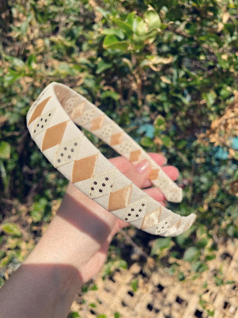 May include: A white headband with a brown and white geometric pattern. The headband is made of a soft, flexible material and has a comfortable fit.