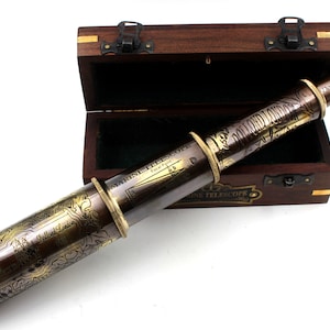 Puede incluir: Un telescopio de latón con grabados intrincados, incluyendo las palabras "Marine Telescope" y "Dollond London 1920." El telescopio está en una caja de madera con un cierre de latón.