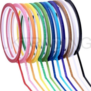 May include: A set of 12 colourful washi tapes, each with a different colour and pattern. The tapes are arranged in a fan shape, with the ends of the tapes trailing off to the right. The tapes are all about 1.2 cm wide.
