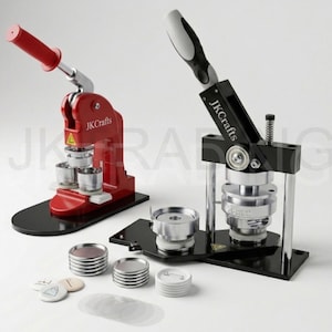 May include: Two button-making machines, one red and one black, with silver components. The red machine has a red handle and the text "JK Crafts". Several button components and finished buttons are also visible.