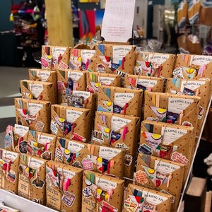 May include: A shelf display of brown paper wrapped packages with colorful stickers and ribbons. The packages are labeled "Reading List" and "Blind Date With a Book!"