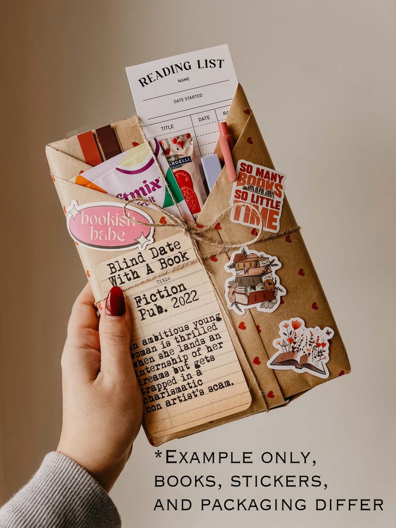 May include: A brown paper package wrapped with twine and decorated with hearts, stickers, and a book titled "Blind Date With A Book: Fiction Pub. 2022". The package also includes a reading list, a bookish babe sticker, and a sticker that says "So many books, so little time".