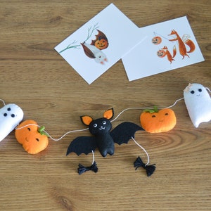 May include: A Halloween garland with black felt bats, ghosts, pumpkins, and cats. The garland is strung with white thread and orange beads.