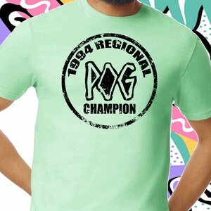 May include: A light green t-shirt with a black and white distressed circle graphic that says "1994 Regional Champion" with the letters "WG" inside the circle.