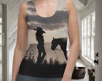 May include: Sleeveless tank top featuring a silhouette of a cowgirl with a horse against a sunset backdrop. The design includes a cowgirl wearing a hat and standing next to a horse. The top is a blend of neutral tones, with a focus on the silhouette.