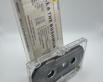 May include: A clear cassette tape case with a black cassette inside, featuring the text "WILL & THE BUSHMEN." The cassette case is labeled with song titles and the SBK Records logo. The cassette tape is a vintage music format.