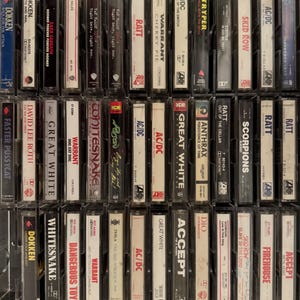 Puede incluir: Una colecci&oacute;n de cintas de casete vintage de varias bandas de rock y heavy metal. Las cintas est&aacute;n en estuches de pl&aacute;stico transparente, con los t&iacute;tulos y nombres de las bandas visibles, incluyendo Dokken, AC/DC y Warrant. Las cintas est&aacute;n dispuestas en una cuadr&iacute;cula.
