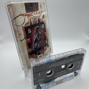 May include: A clear cassette tape and case featuring the album "Gravity Dance" by The Horse Flies. The case has a colorful, abstract design with the band's name. The cassette tape displays the track list and MCA Records information.