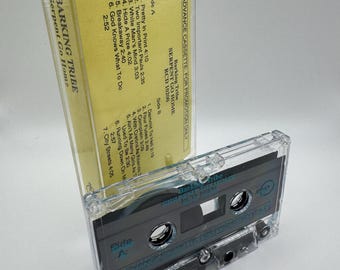 May include: A clear cassette tape case with a yellow insert. The insert features the text "Barking Tribe Serpent Go Home" and a tracklist. The cassette tape is labeled "Side A" and "Advance Cassette: For Promotion Only."