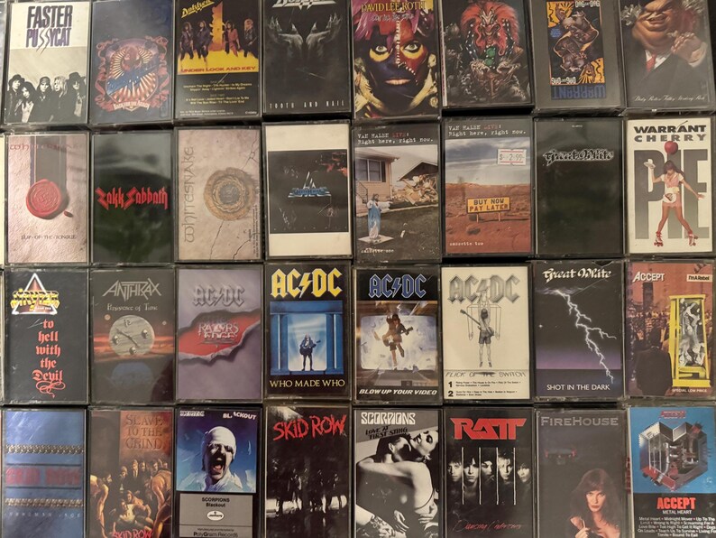 Puede incluir: Una colecci&oacute;n de cintas de casete vintage con varias bandas de rock y metal. Se ven t&iacute;tulos de &aacute;lbumes y nombres de bandas, como AC/DC y Skid Row. Las cintas est&aacute;n en estuches de pl&aacute;stico transparente.