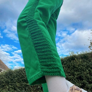 May include: Green pants with a contrasting green crocheted stripe down the side.