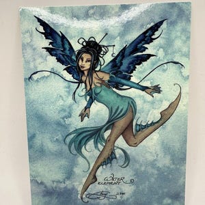 May include: A watercolor illustration of a fairy with dark hair and blue wings. The fairy is wearing a teal dress and is posed mid-air against a cloudy blue background. The text "Water Element" is visible.
