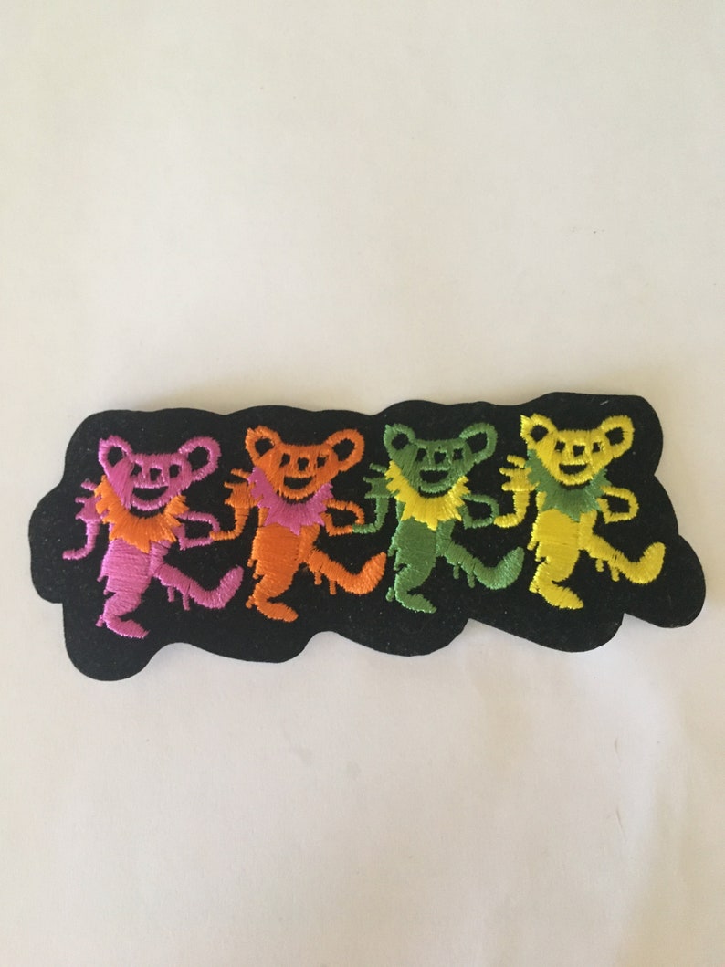 May include: Four colorful dancing bears embroidered on a black patch. The bears are pink, orange, green, and yellow.