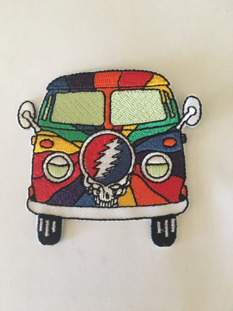 May include: A colorful embroidered patch of a psychedelic van with a Grateful Dead skull and lightning bolt logo on the front.