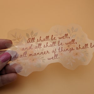 May include: A clear sticker with a floral design and the text "All shall be well, and all shall be well. And all manner of things shall be well."