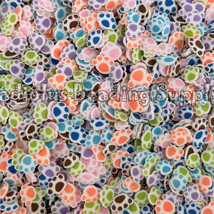 May include: A large assortment of colorful paw print shaped resin flatbacks. The paw prints are in various colors including blue, green, pink, orange, purple, and brown.